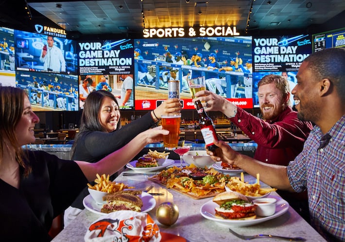 Two men and two women drinking and dining at Sports & Social sports bar.