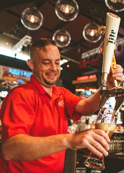 Careers: A smiling bartender fills a pint glass from the tap, just one of the exciting opportunities available!
