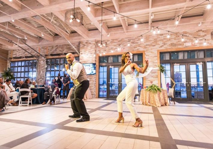 A groom in his bow tie and vest and a bride in a lace top and white pants command the dance floor, to their guests' delight!