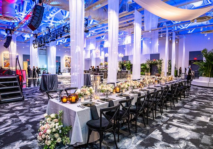 A gorgeous ballroom features ceiling-to-floor translucent accent panels, and a perfectly set wedding table awaits the guests!